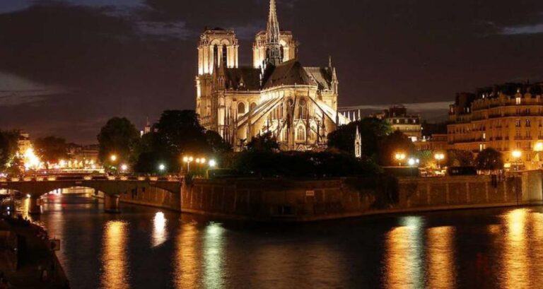 Cathedral illuminated at night by river.