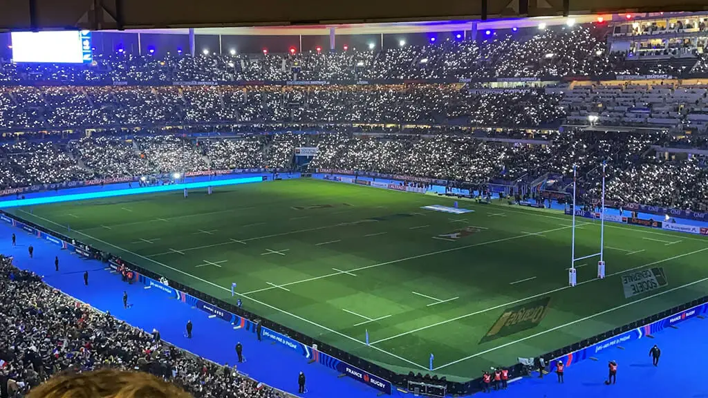 Stade de football plein durant un match nocturne.